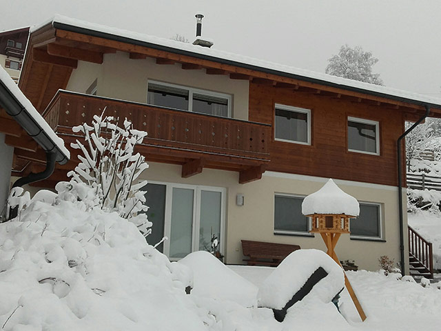 Voorzijde van het chalet in de winter, met besneeuwde tuin