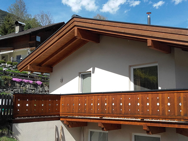 Het houten balkon en de overstekende dakrand van het chalet