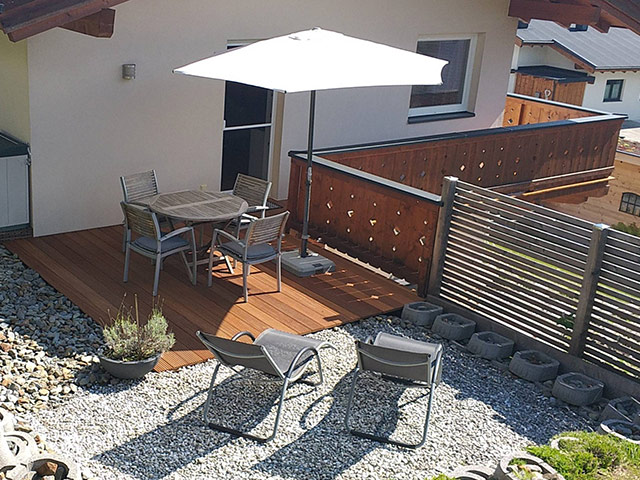 Terras met parasol, tafel, stoelen en ligstoelen
